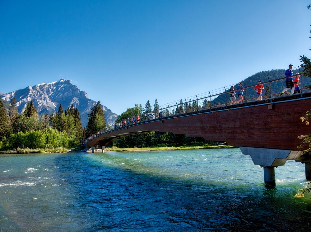 Runners cross the Banff Pedestrian Bridge.